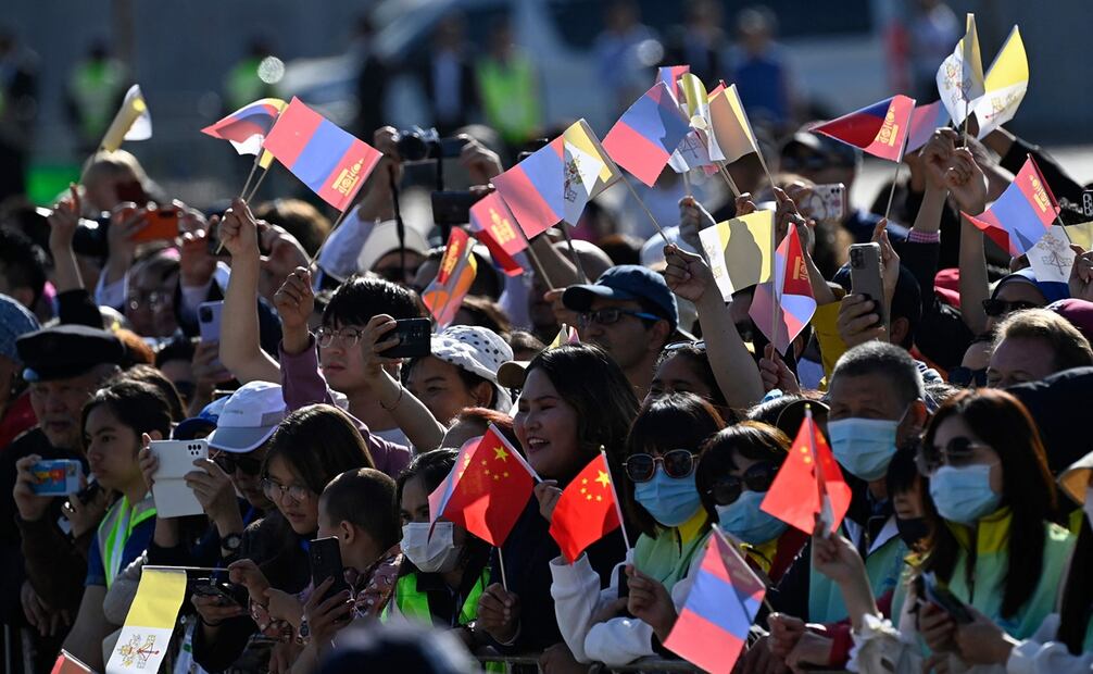 Simpatizantes, portando banderas del Vaticano y Mongolia, durante una ceremonia de bienvenida al papa Francisco en la plaza Sukhbaatar en Ulán Bator. Foto: AFP