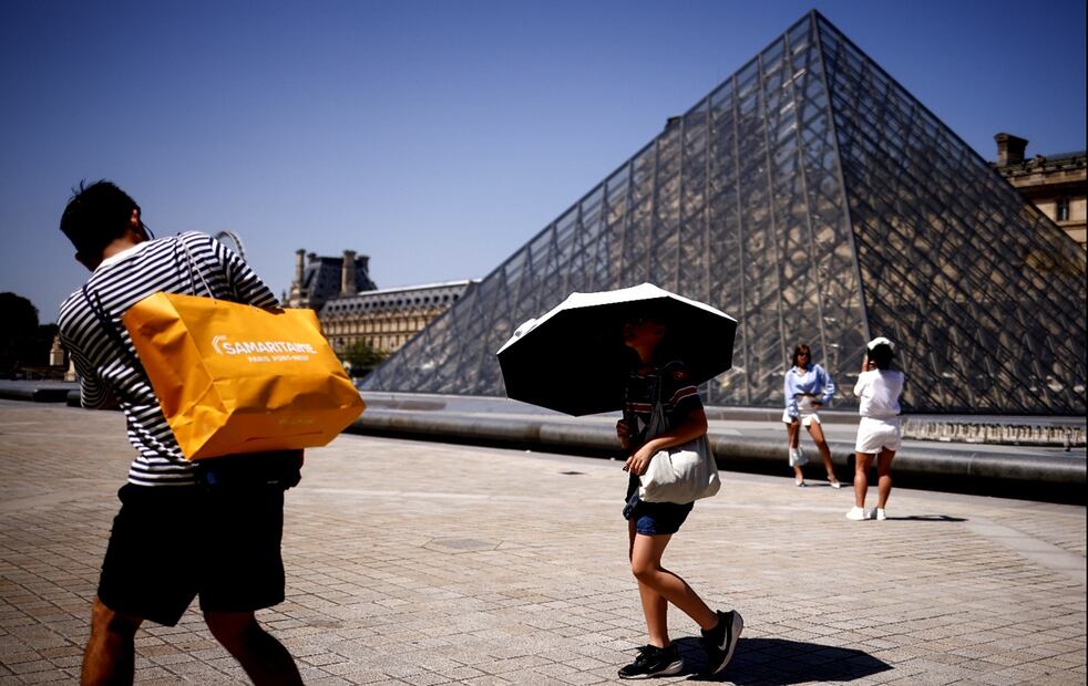 Turistas se toman fotos con paraguas para protegerse del sol durante una ola de calor en el Museo del Louvre de París, Francia, el 1 de julio de 2025. Foto: EFE
