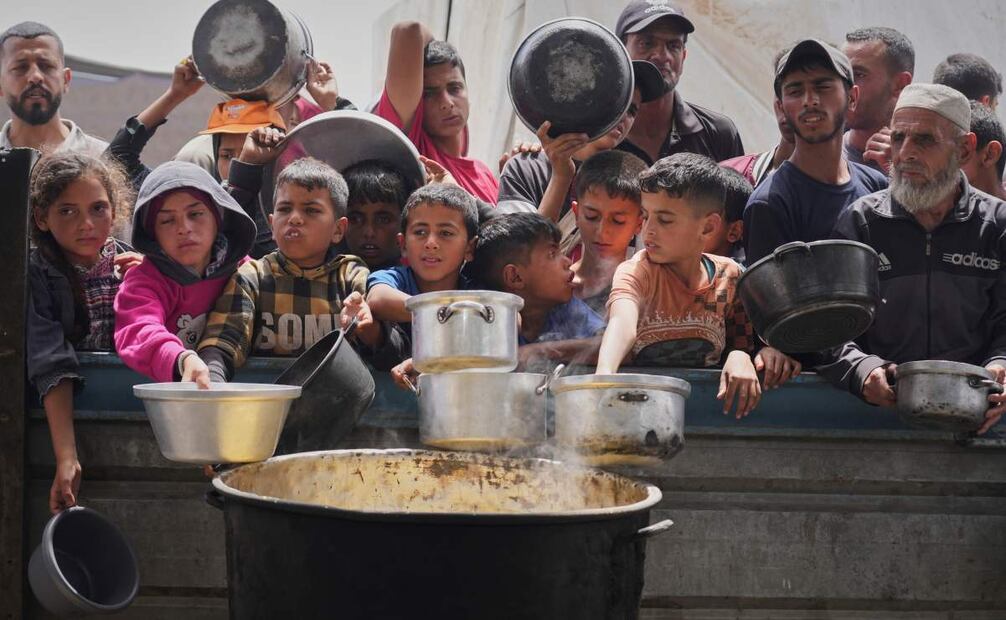 Niños y adultos palestinos esperan para recibir comida en una cocina comunitaria en Jan Yunis, en el sur de la Franja de Gaza. Foto: AP