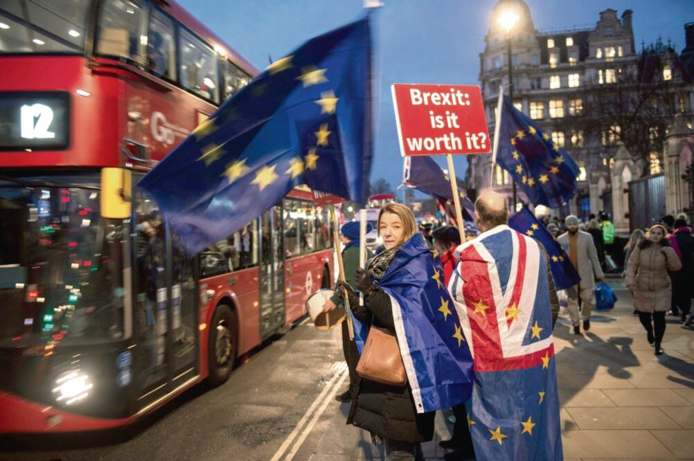 Manifestantes en contra del Brexit protestan con pancartas y la bandera de la Unión Europea afuera de la sede del Parlamento británico, en Londres, un día antes de que la Cámara de los Comunes vote el plan sobre la salida de Reino Unido de la EU (AFP)