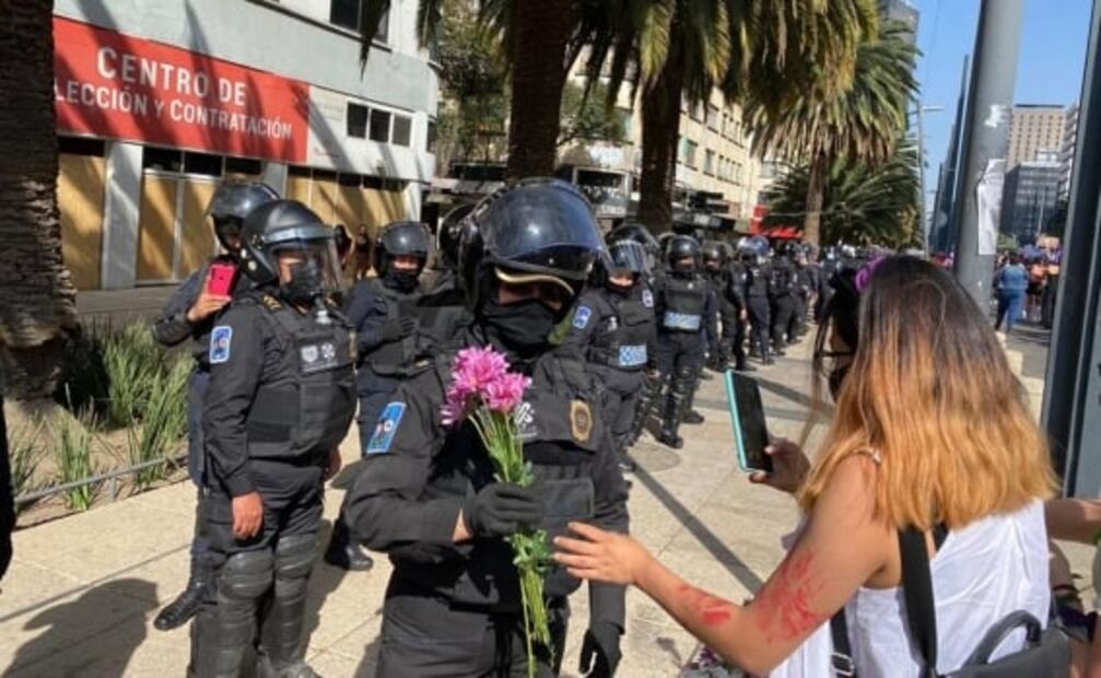 Mujeres policías reciben flores de manifestantes durante marcha del 8M 