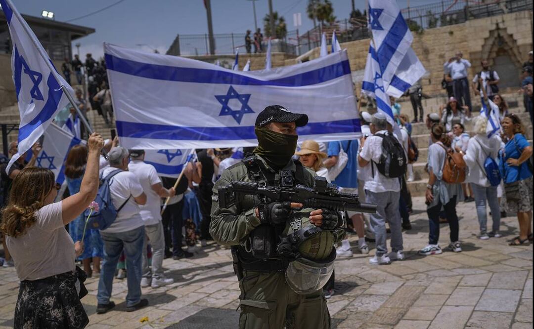 Un agente de la policía de Israel hace guardia mientras israelíes ondean banderas nacionales previo a la marcha por el Día de Jerusalén, un feriado israelí que conmemora la captura de Jerusalén Este en la Guerra de los Seis días en 1967. Foto: AP