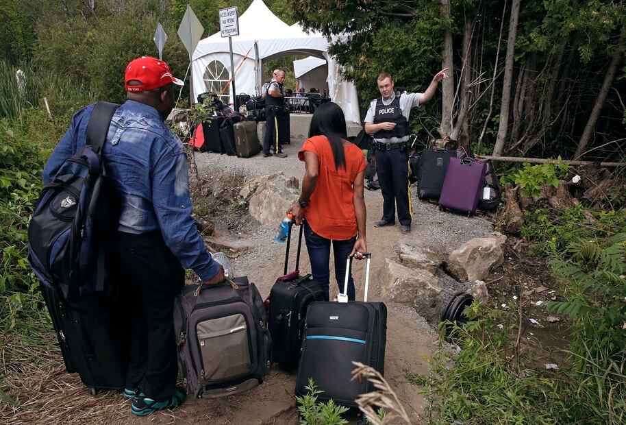 Un agente de la Real Policía Montada de Canadá informa a una pareja de migrantes sobre la ubicación de una estación fronteriza legal, poco después de que cruzaron ilegalmente desde Champlain, Nueva York. FOTO: AP