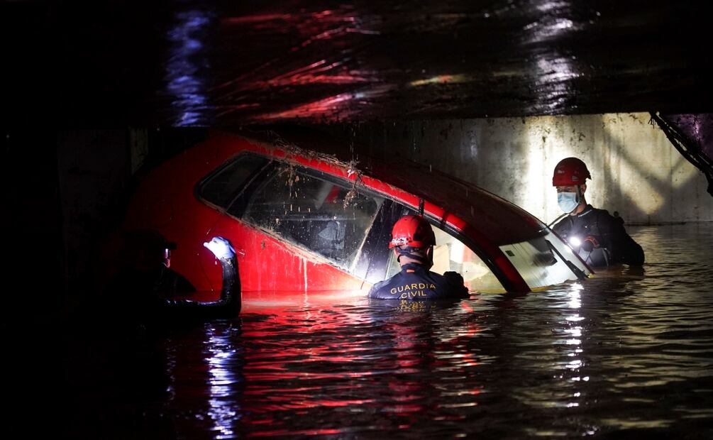 Elementos de la Guardia Civil caminan en un estacionamiento inundado para examinar automóviles en busca de cuerpos, en Paiporta, cerca de Valencia, España. Foto: AP