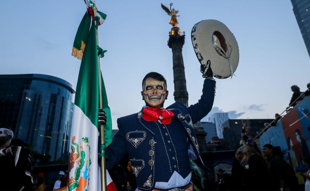 Con una mano en la bandera y la otra en el sombrero, personas buscan darle vida a la imagen ancestral de los catrines. (27/10/2024) Foto: Axel Sánchez/ El Universal