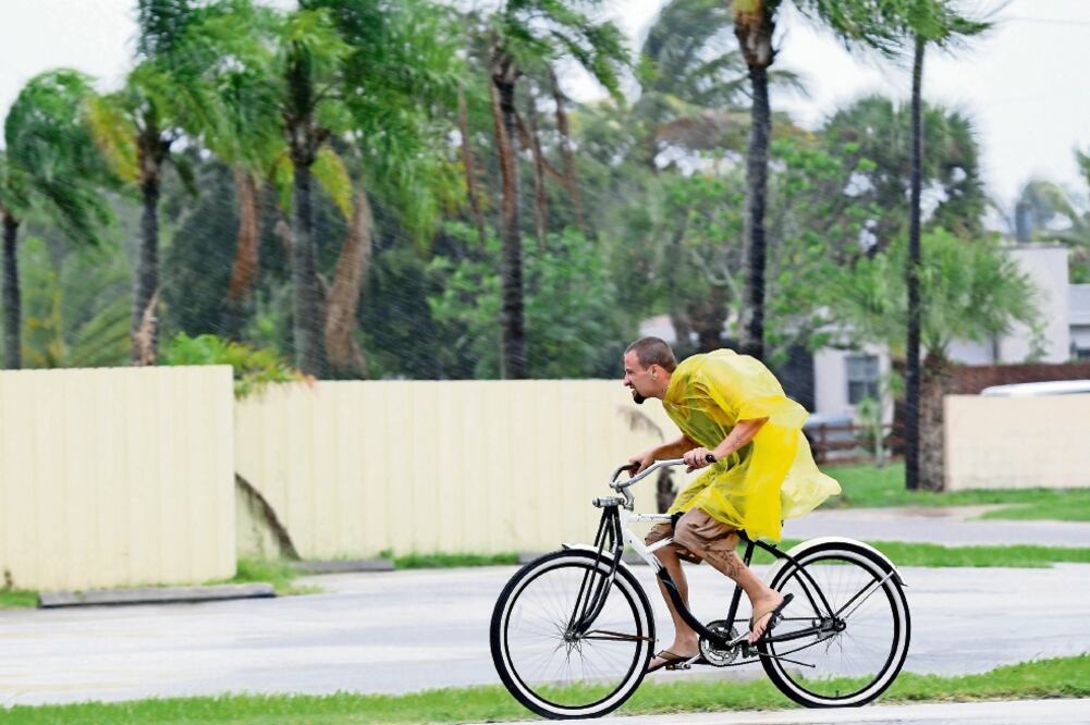 Un ciclista se traslada bajo la lluvia, en Cabo Cañaveral, Florida, donde los negocios cerraron sus puertas ante el riesgo del fenómeno meteorológico (JOHN RAOUX. AP)