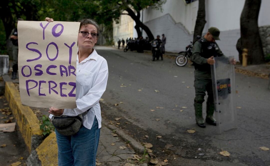 Una mujer que dijo ser una seguidora del extinto exoficial de policía rebelde Oscar Pérez muestra un cartel que dice en español "Soy Oscar Pérez" en un puesto de control cerca de la morgue (Foto: AP)