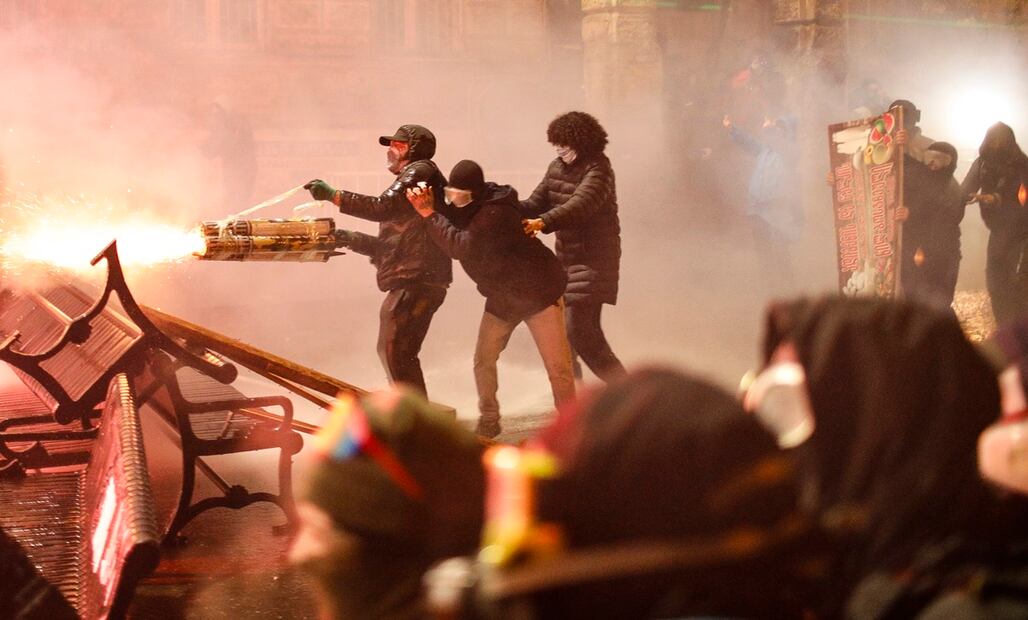 Partidarios de la oposición georgiana lanzan fuegos artificiales hacia la policía durante una protesta frente al edificio del Parlamento en  Tiflis. Foto: EFE