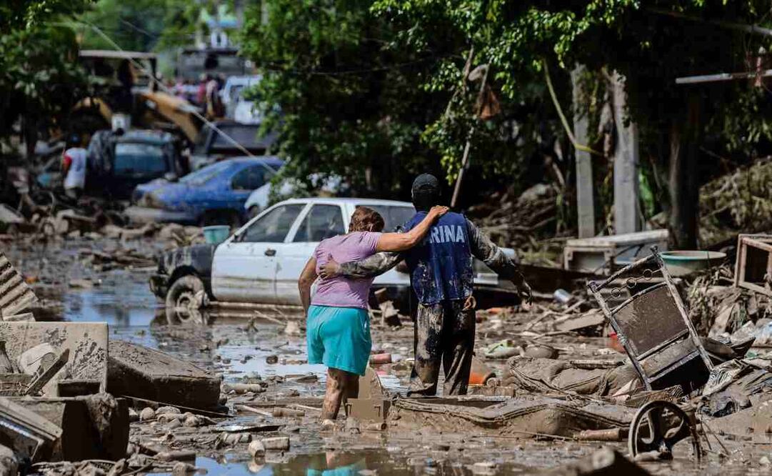 En Poza Rica, Veracruz, un elemento de la Marina ayuda a una mujer a cruzar la calle, que se encuentra cubierta de lodo, basura y escombros luego del desbordamiento del río. Foto: Félix Márquez / AP