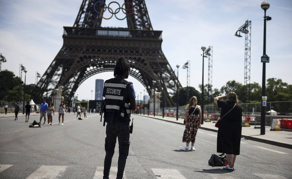 oficial de seguridad observa a personas tomándose fotos frente a la Torre Eiffel antes de los Juegos Olímpicos. Foto: AP