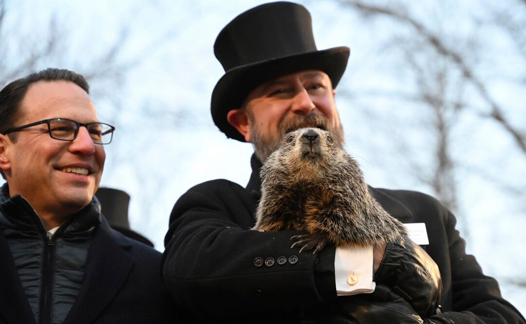 El manejador del Groundhog Club A.J. Dereume sostiene a Punxsutawney Phil mientras que el gobernador de Pensilvania, Josh Shapiro, observa durante la celebración número 137 del Día de la Marmota en Gobbler's K. Foto: AP