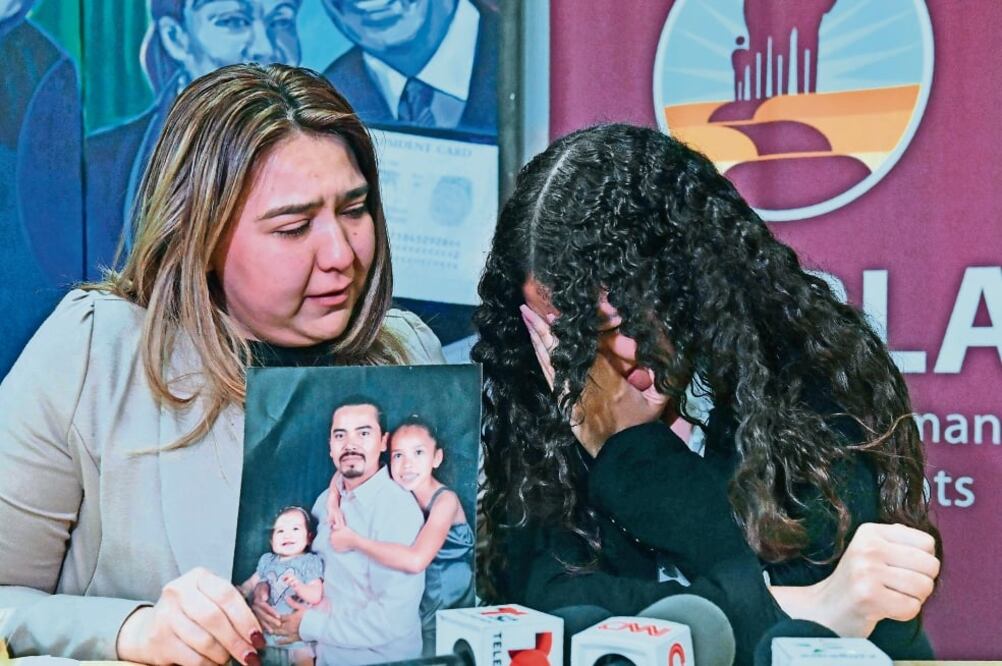 Ana Castillo muestra la foto de su esposo, detenido por las autoridades migratoria s, mientras consuela a su hija durante una conferencia en Los Ángeles. (FREDERIC J. BROWN. AFP)