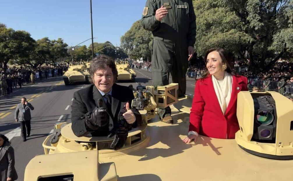 Momento en el que el presidente Milei y su vice, Victoria Villarruel, aprovecharon para bajar del palco y se subieron a uno de los blindados, saludando al público presente, mientras recorrían un tramo del desfile con todos sus custodios de seguridad caminando alrededor del vehículo. Foto: EFE