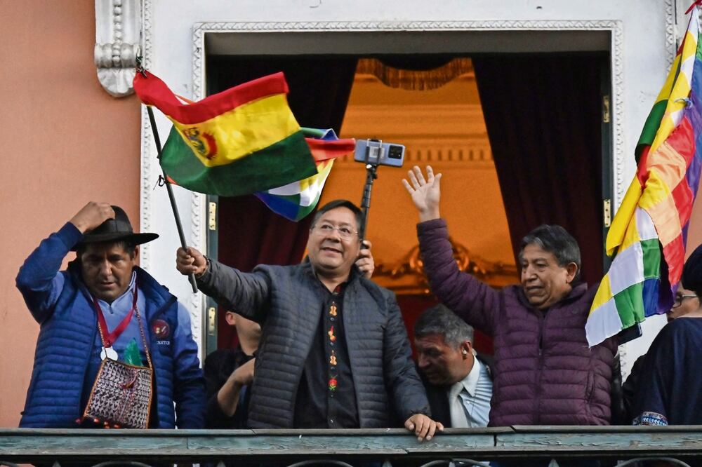 El presidente boliviano Luis Arce ondea una bandera de su país en el balcón del Palacio de Gobierno en La Paz, tras el movimiento militar. Foto: de Aizar Raldes. AFP