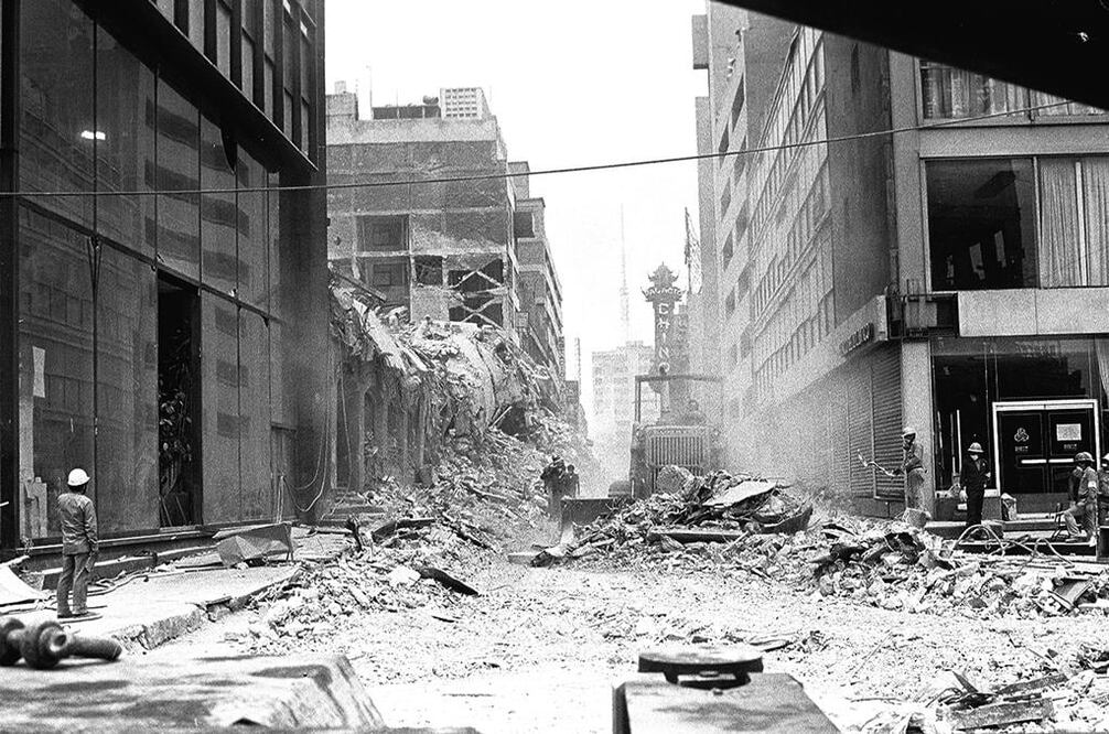 Fotografía del archivo de El Universal en la que se aprecian los trabajos de remoción de escombros del Conalep, en la calle de Iturbide, que colapsó tras los sismos de 1985. La imagen fue captada desde la esquina de la avenida Juárez; del lado izquierdo se aprecia el edificio que compartían oficinas de Conasupo y Gobernación. Al fondo se alcanza a ver el letrero del cine Palacio Chino. 