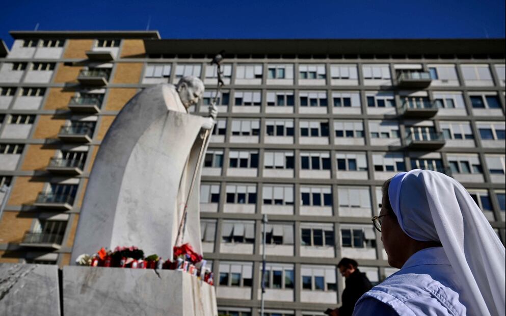 Una monja reza ante la estatua de Juan Pablo II en donde se ha instalado un altar afuera del hospital Gemelli, en Roma, donde el Papa Francisco está hospitalizado, el 21 de febrero de 2025. Foto: AFP