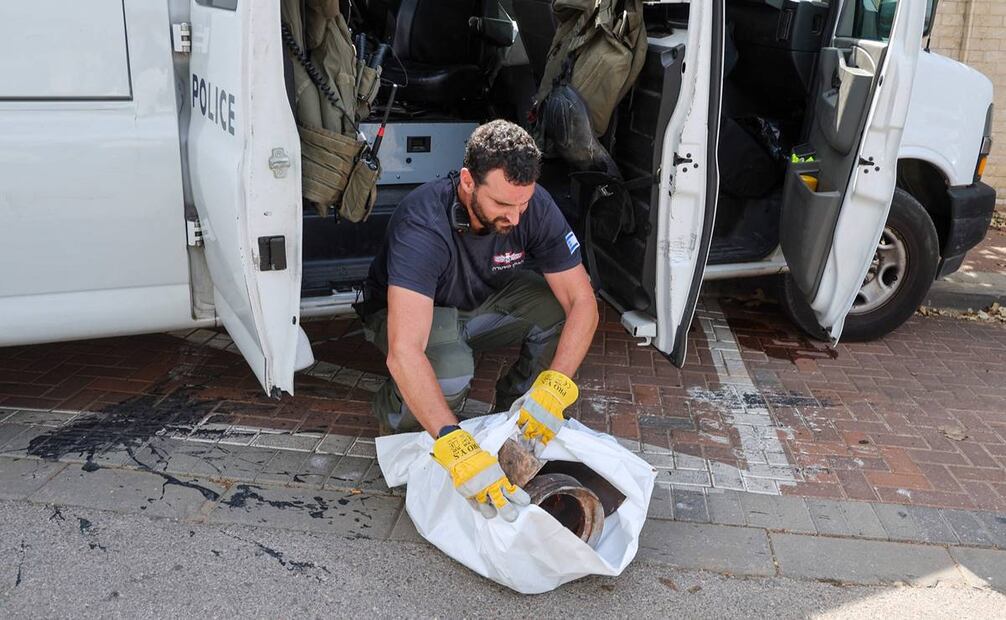 Un miembro del escuadrón antiexplosivos de la policía israelí recoge escombros después de que un cohete disparado por Hamas. FOTO:AFP