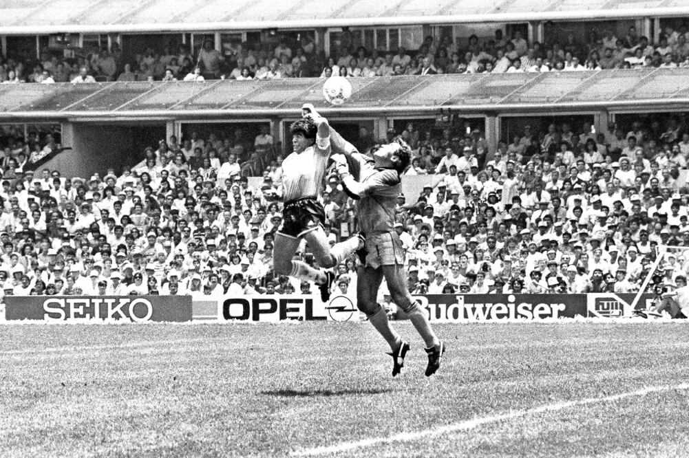 Ante la salida del portero inglés Peter Shilton, Maradona salta, pero remata ayudado con el puño; el árbitro validó (ARCHIVO. EL UNIVERSAL)