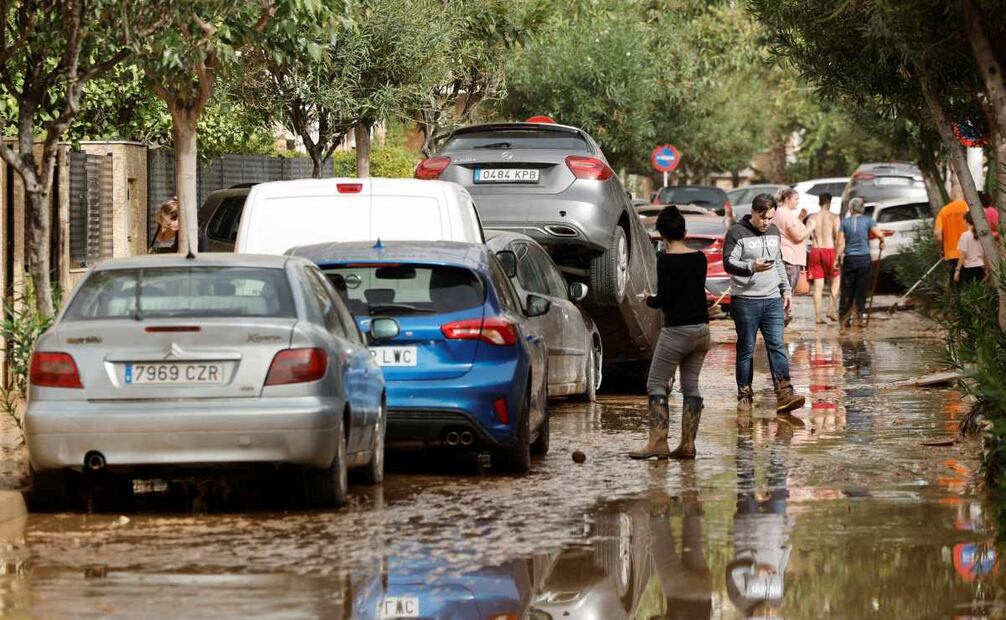 Varias personas junto a vehículos dañados por las intensas lluvias de la fuerte dana que afecta especialmente el sur y el este de la península ibérica, este miércoles en Picaña (Valencia). Foto: EFE