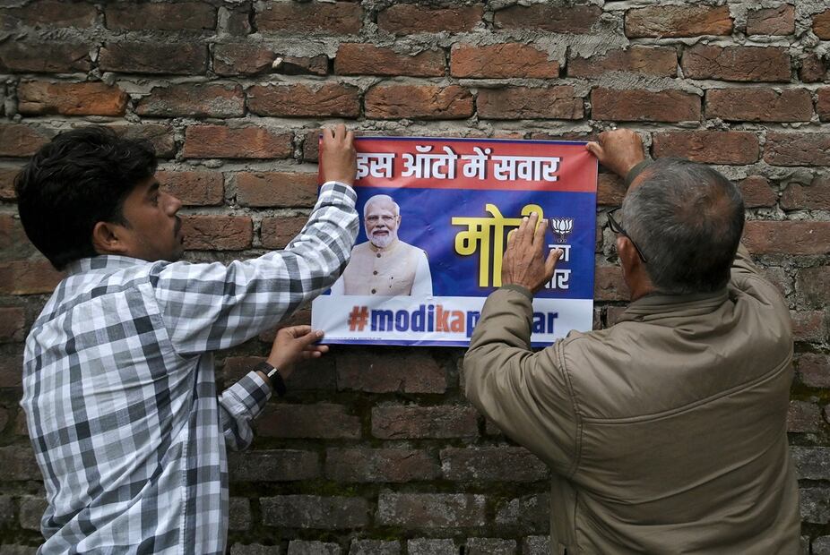 Activistas del Partido Bhartiya Janta (BJP) pegan una cartulina con la imagen del líder del BJP y primer ministro indio, Narendra Modi, en una pared cerca de un colegio electoral durante la primera fase de votación de las elecciones generales de India en Jammu. Foto: AFP