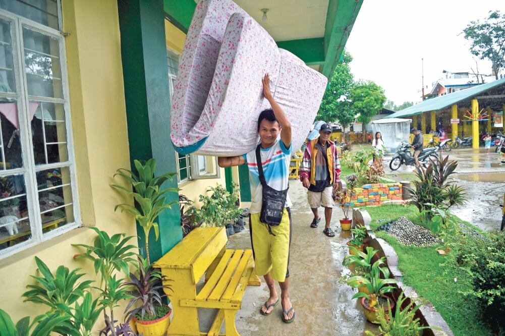 Un filipino lleva un colchón a un salón de clases que es usado como un refugio en Tuguegarao, en la provincia de Cagayán. TED ALJIBE. AFP