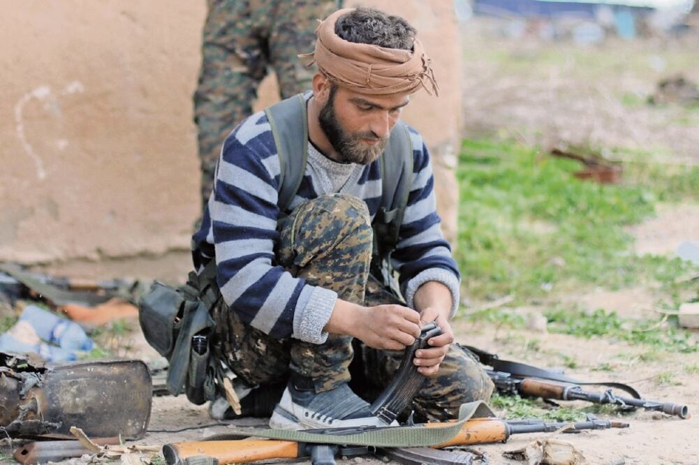 Batalla. Un combatiente de las Fuerzas Sirias Democráticas recarga su arma en Al Baguz, durante el ataque al Estado Islámico. (RODI SAID. REUTERS)