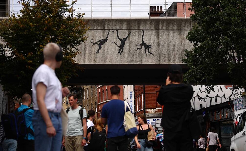 La gente pasa junto a una obra de arte del artista callejero Banksy. Foto: AFP
