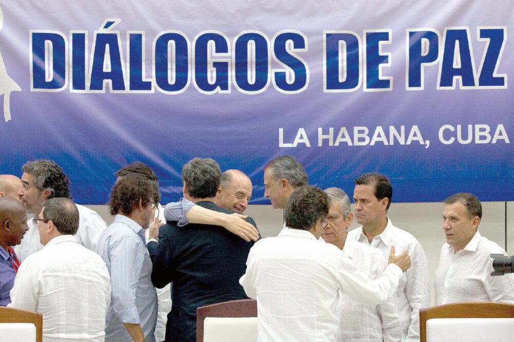 Miembros del equipo negociador del gobierno de Colombia, de la guerrilla de las FARC y observadores internacionales se abrazaron ayer en La Habana despué s de la firma de un acuerdo de paz (RAMÓN ESPINOSA. AP)
