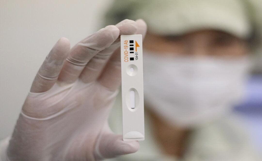 An employee holds up an antibody test cartridge - Photo: Lee Jin-man/AP