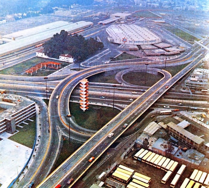 El cruce de la Calzada de Tlalpan, la Calzada Taxqueña y la avenida Miguel Ángel de Quevedo en los años setenta. En el centro destaca la escultura "La gran espiga", obra de Fernando González Gortázar; a la izquierda está el Instituto Cultural y en el fondo se encuentran la estación del Metro Tasqueña y la tienda MÁS, que después se convirtió en Gigante y luego en Soriana. Imagen: Col. Villasana.