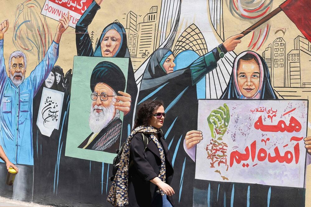 Una mujer iraní pasa junto a un mural antiestadounidense y antiisraelí, en Teherán. FOTO: ATTA KENARE. AFP
