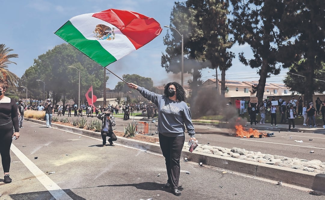 A protester waves a Mexican flag as protestors and federal agents clash near a Home Depot after a raid was conducted by Immigration and Customs Enforcement. Photo: EFE/EPA/ALLISON DINNER