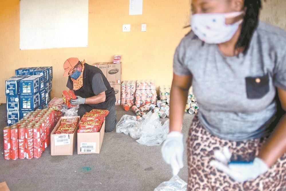 Voluntarios preparan alimentos y productos de limpieza para distribuir ante el Covid-19 en Johannesburgo, Sudáfrica. Foto: LUCA SOLA. AFP