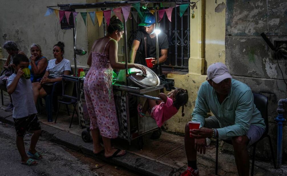 Una mujer compra sopa a un vendedor ambulante durante un corte de energía en La Habana, el lunes 21 de octubre de 2024. Foto: AP