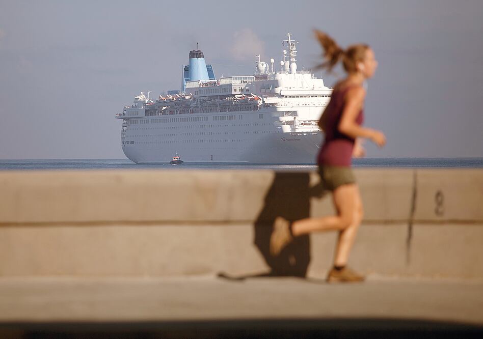 En esta fotografía de archivo del 19 de marzo de 2015, una mujer trota en el Malecón de La Habana mientras el crucero Thomson Dream llega a la bahía