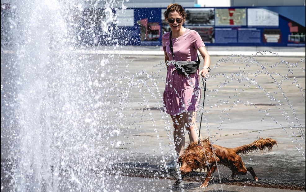 Una mujer acerca a su perro para que se refresque en la fuente de la Piazza Castello en Turín, Italia (01/07/2025). El Ministerio de Salud italiano declaró alerta roja en todo el país debido a las temperaturas extremas. Foto: EFE