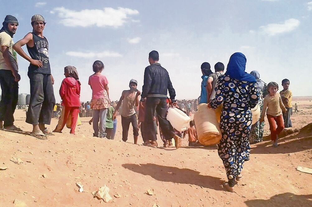 Refugiados sirios se reúnen en busca de agua en el campamento de Rubkan, en la frontera noreste de Jordania con ese país (AP)