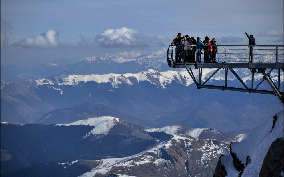 Visitantes posan para fotografías mientras se encuentran en una plataforma de observación del Pic du Midi, un complejo de observatorios en la cima de una montaña de 2.876 metros con los Pirineos al fondo en La Mongie, suroeste de Francia, el 21 de febrero de 2025. Foto: AFP