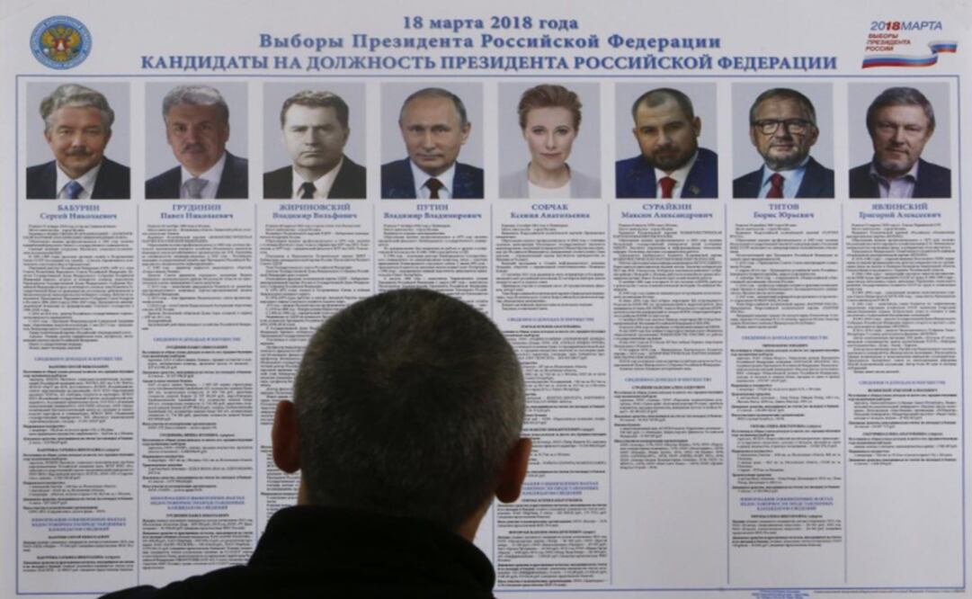 A voter looks through a broadsheet with information about the candidates during the early voting ahead of the March 18 Presidential Election – Photo: Sergei Karpukhin