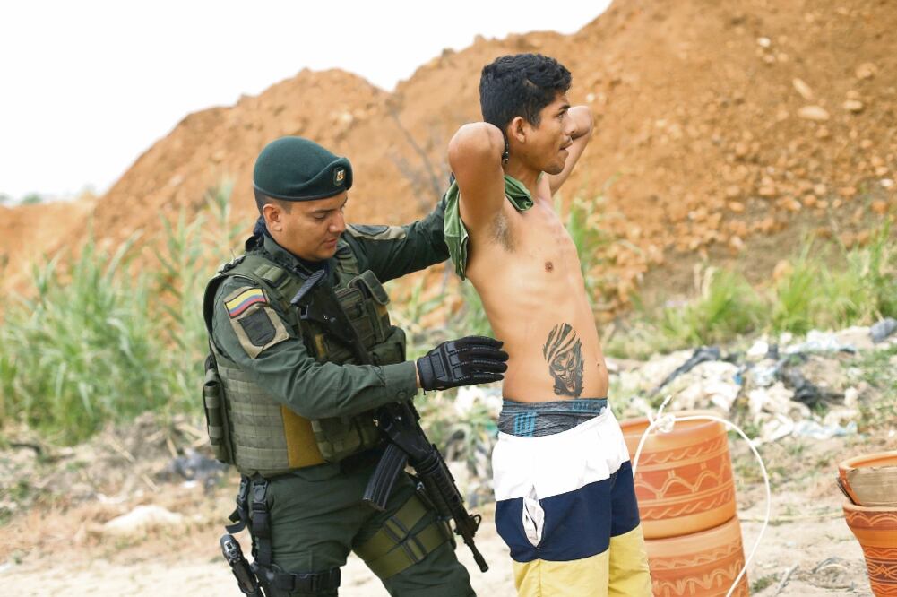 Un policía colombiano revisa a un hombre mientras patrulla los senderos en una operación de lucha contra el contrabando en Cúcuta, frontera con Venezuela. (REUTERS)