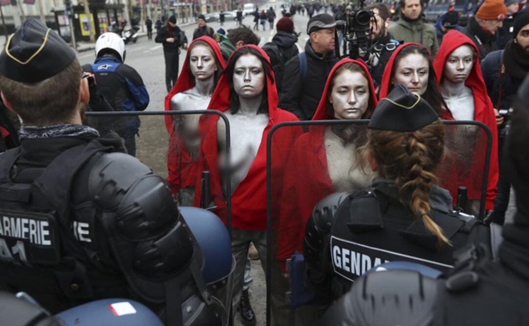 Cinco mujeres con piel pintada de color plateado y vestidas con una sudadera color rojo sorprendieron cuando encararon a la policía de Francia. Foto: AFP 