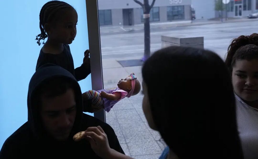 Charlotte, una inmigrante venezolana, vista a contraluz sosteniendo una muñeca mientras sus familiares y otras personas se resguardan, en la estación del 16to Distrito del Departamento de Policía de Chicago. Foto: AP