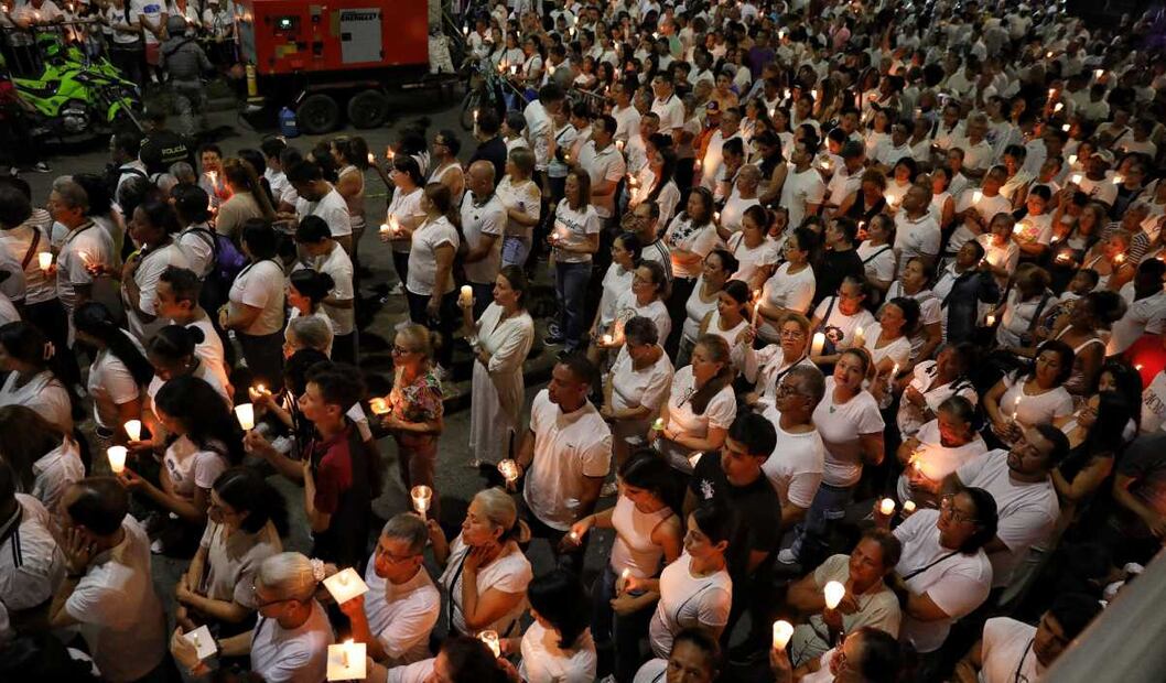 La gente sostiene velas frente a la base aérea de Cali, Colombia, durante una vigilia en honor a las víctimas de un coche bomba que explotó. (24/08/25) Foto: AP
