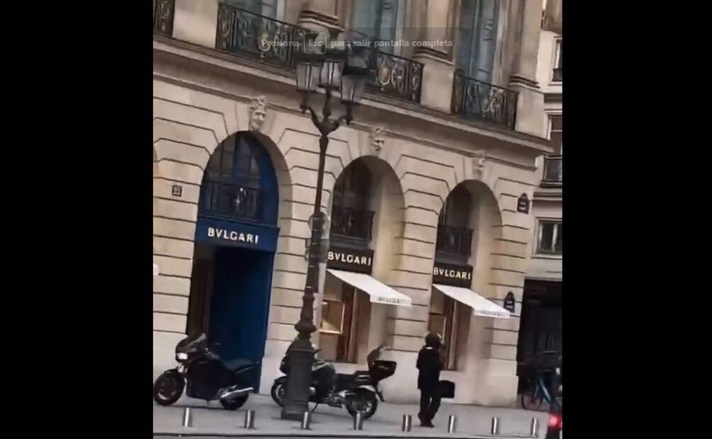 Dos motocicletas negras estacionadas en la acera, frente a la joyería, mientras un hombre con casco, armado y vestido de negro, vigila el lugar. Foto: Twitter / Captura de pantalla