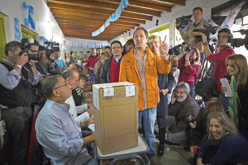 Daniel Scioli (centro), en compañía de su esposa Karina Rab o l l i n i (centroderecha), antes de emitir su voto en una escuela primaria de la localidad de Dique Luján, a 50 kilómetros de Buenos Aires (MARTIN ZABALA. XINHUA)