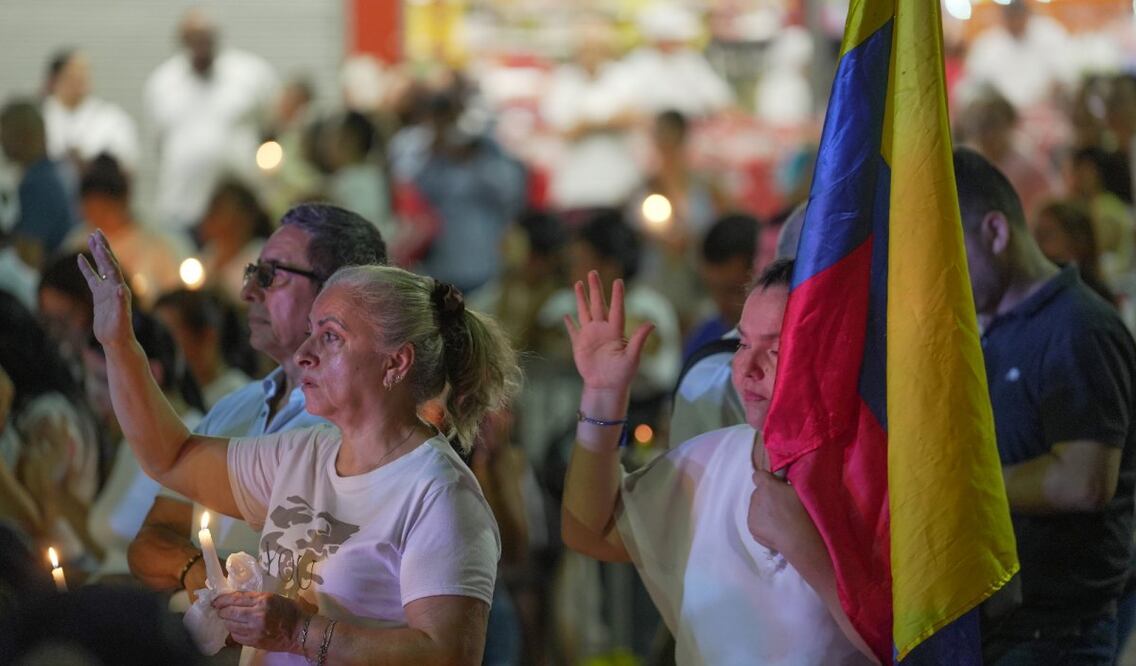 La gente sostiene velas frente a la base aérea de Cali, Colombia, durante una vigilia en honor a las víctimas de un coche bomba que explotó. (24/08/25) Foto: EFE