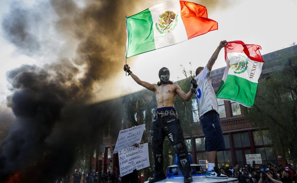 Manifestantes ondean banderas mexicanas mientras se incendian autos durante las protestas provocadas por las redadas migratorias en Los Ángeles, California, el 8 de junio de 2025. Foto: EFE