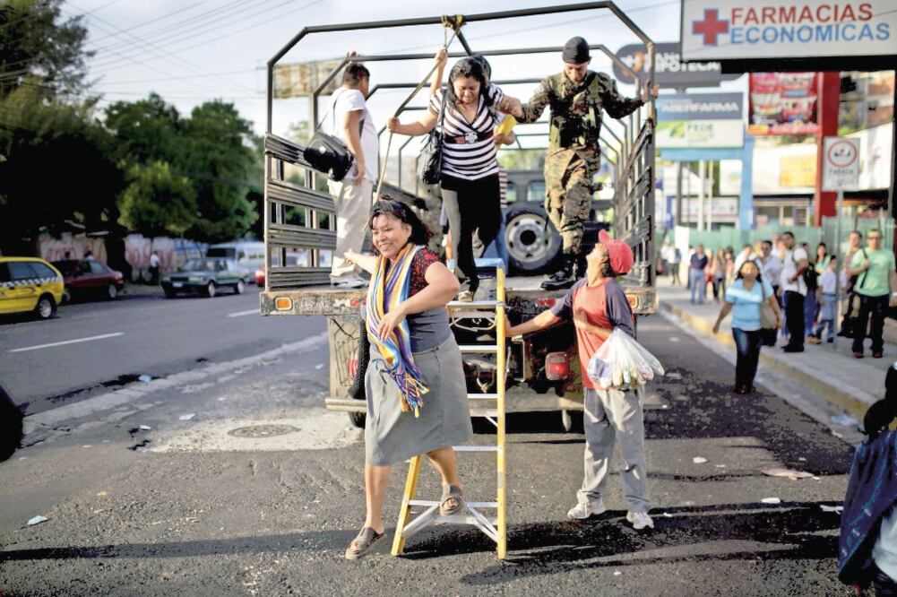 Salvadoreños descienden de un camión del ejército, en el cuarto día del paro de transporte público, en San Salvador. El gobierno aseguró que “lo peor ha pasado” y que 50% del servicio en el noreste capitalino está operativo (JOSÉ CABEZAS. REUTERS)