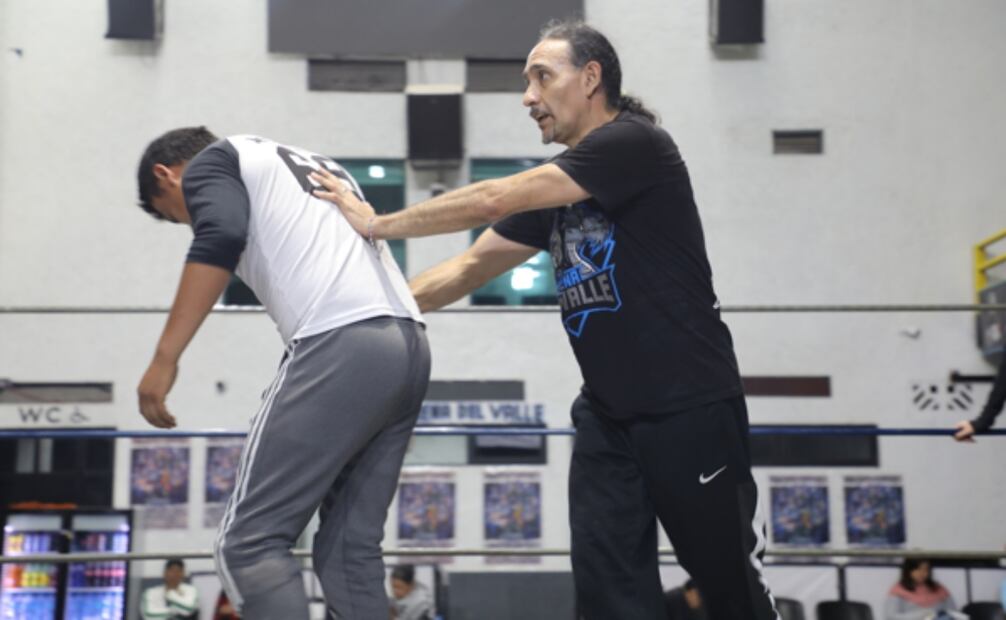 Guerrero Nocturno, luchador y profesor de lucha libre corrigiendo un ejercicio a un alumno durante sus clases en la Arena del Valle. Foto: David Martínez