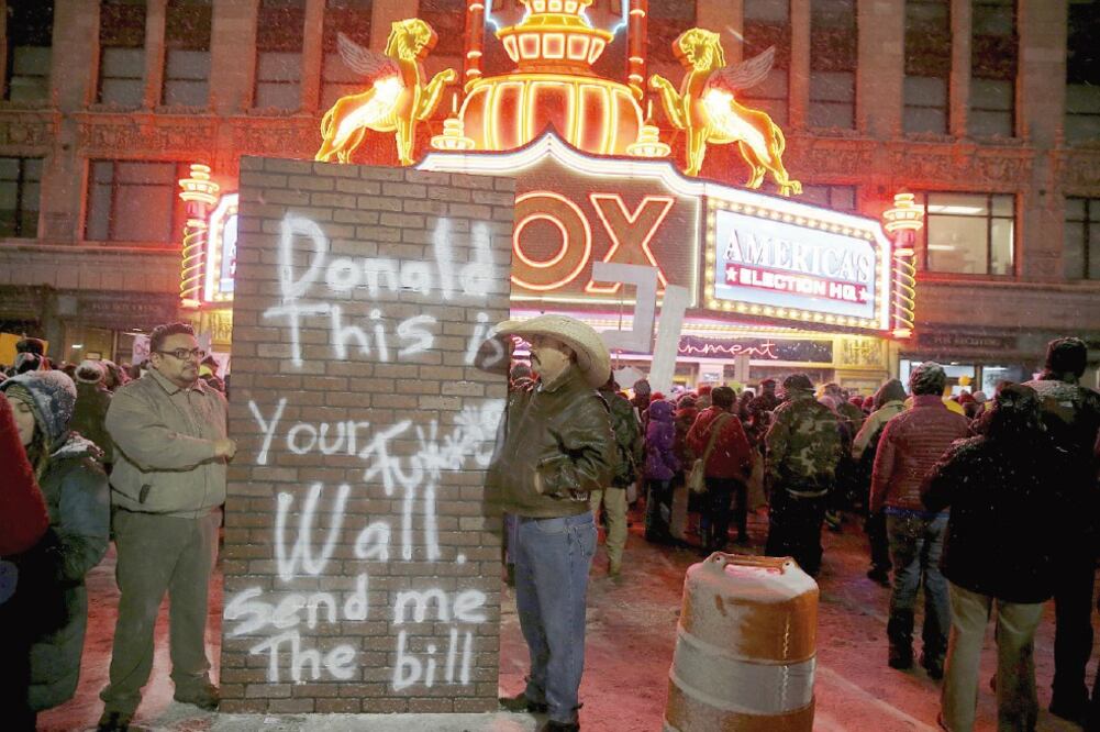 Detractores de Trump se manifestaron el jueves en Detroit. El letrero dice: “Donald, este es tu maldito muro. Mándame la cuenta” (CARLOS BARRIA. REUTERS)